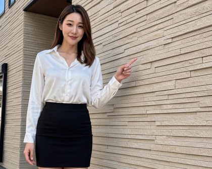 세라믹사이딩으로 마감한 주택 외벽을 가리키며 소개하는 안내 모델(AI 가상 인물)