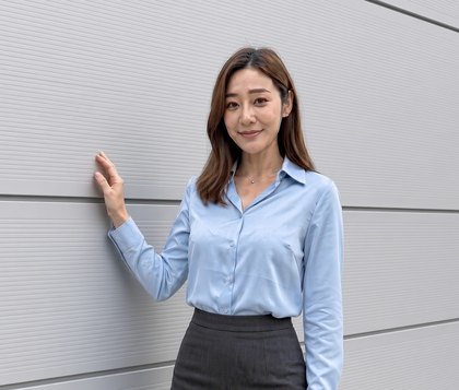 은회색 500골 판넬로 마감한 건물 벽 앞에서 한 손으로 벽을 짚고 웃는 안내 모델(AI 가상 인물)